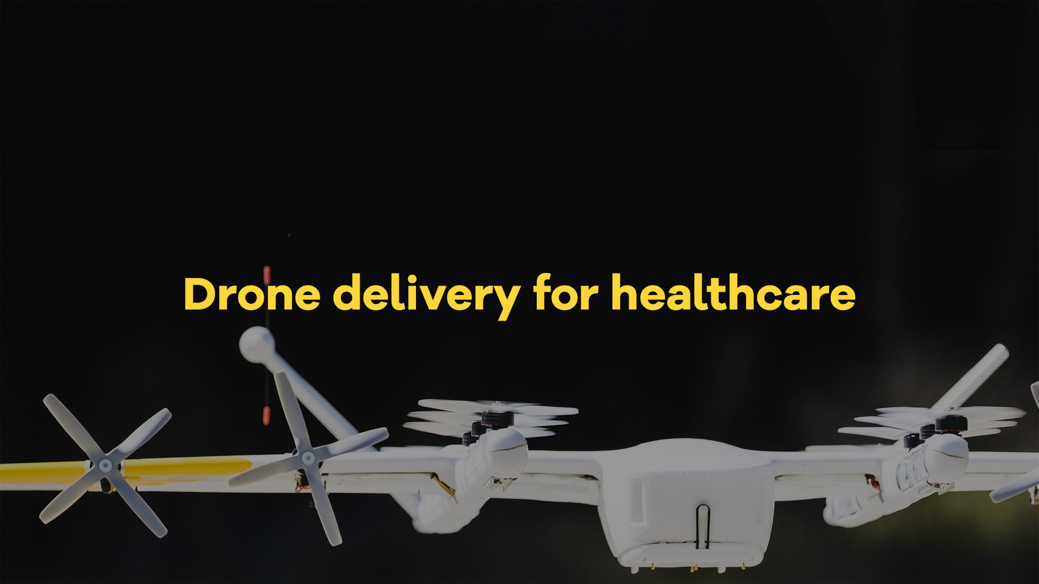 A white drone with multiple rotors hovers against a dark background, featuring the text "Drone delivery for healthcare" in yellow, highlighting the innovative use of drones in medical logistics.